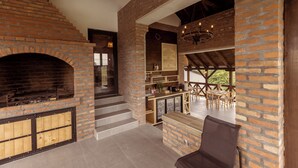Un interior rústico con chimenea de ladrillo, escalera de madera y zona de comedor con asientos exteriores.
