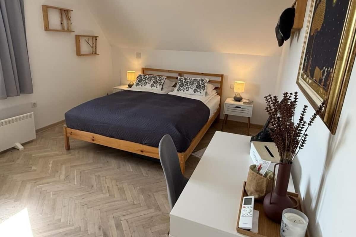 Un dormitorio con cama, mesitas de noche, escritorio y una silla.