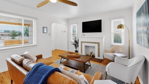 Una sala de estar moderna con chimenea, ventilador de techo y televisor de pantalla plana.