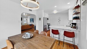 Una cocina moderna con armarios blancos, una mesa de comedor de madera y taburetes rojos.