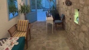 Una habitación acogedora con techo alto, una mesita con sillas, un sofá y vistas a un espacio exterior a través de un ventanal.