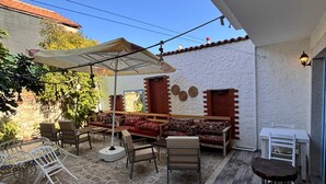 Un patio exterior con una mesa y sillas, un sofá y una pequeña mesa con una silla.