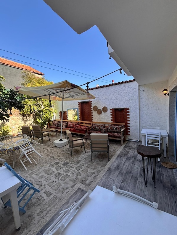 Um pátio externo com mesa e cadeiras, um sofá e uma mesinha com uma cadeira.