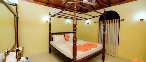 A four-poster bed with a wooden frame and a ceiling fan above.