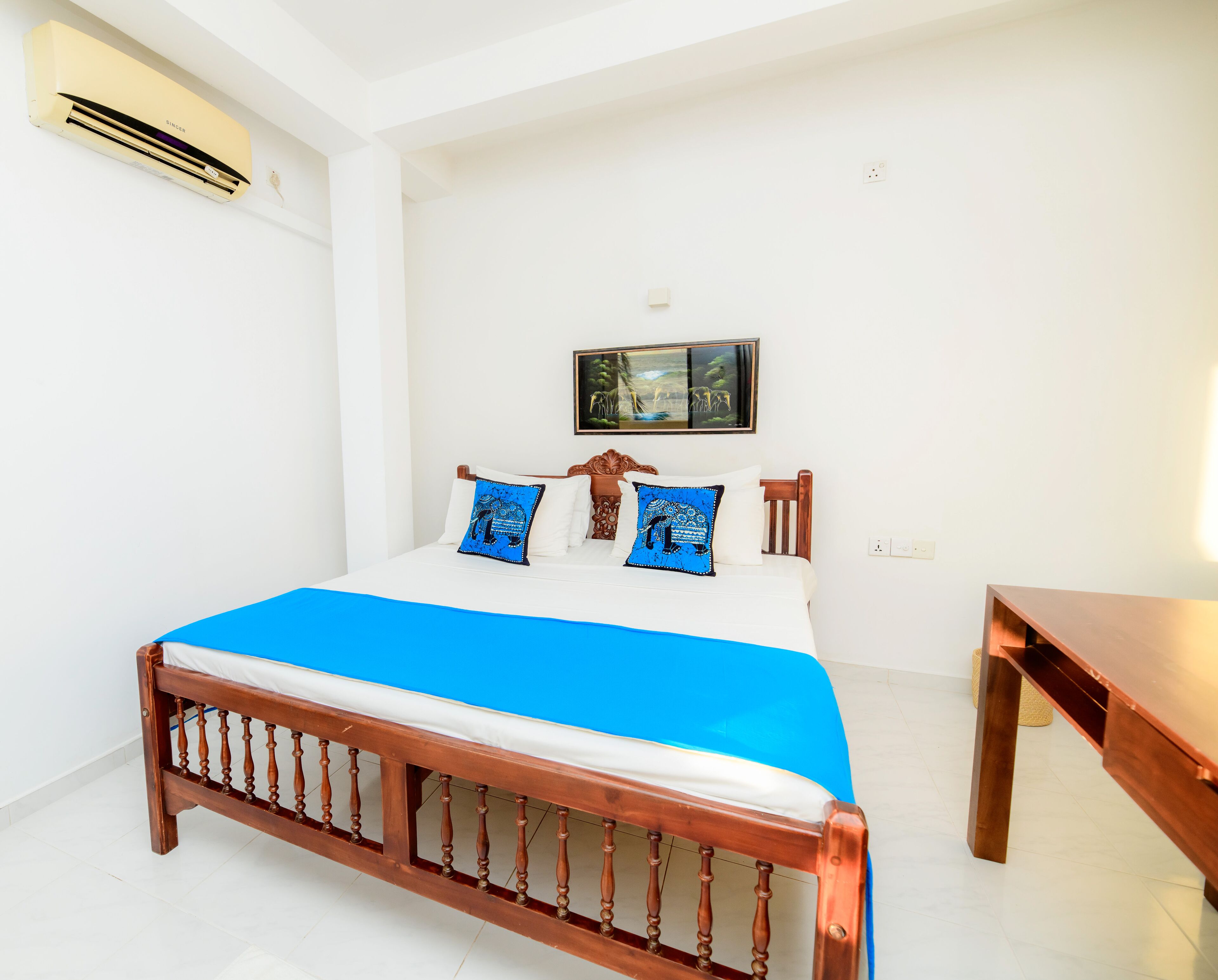 A bedroom with a bed, a wooden headboard, a painting on the wall, and a small table.