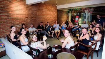 A group of people seated around a table in a room with brick walls and a glass partition displaying "HAPPY NEW YEAR".