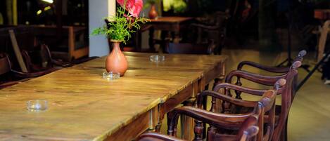 A long wooden dining table with chairs, a vase with flowers, and a modern ceiling with recessed lighting.