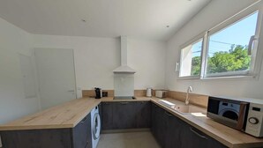 Eine kompakte Küche mit Waschmaschine, Backofen und einem Fenster für natürliches Licht.