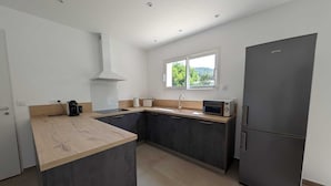 Eine moderne Küche mit dunklen Schränken, einer Holz Arbeitsplatte, einem eingebauten Backofen, einer Mikrowelle und einem Kühlschrank.