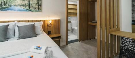 Une chambre d’hôtel comprenant un lit, une table de chevet, une armoire en bois, un bureau et une chaise.