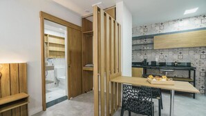 Μια μικρή κουζίνα με ξύλινα ντουλάπια, ένα τραπέζι φαγητού και μια μαύρη καρέκλα.