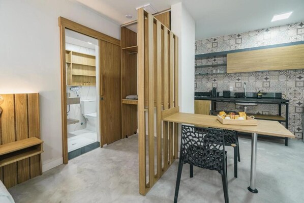 A compact kitchen with wooden cabinets, a dining table, and a black chair.