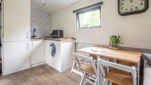 Una cocina con armarios blancos, una mesa de madera y un reloj en la pared.