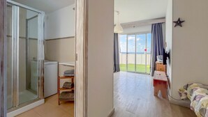 Hotelkamer met een schuifdeur naar een balkon, een kleine kitchenette, een bed met een kleurrijke deken en een ster decoratie aan de muur.