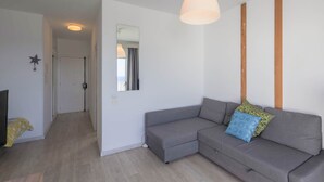 Een moderne woonkamer met een grijze modulaire bank, een hangende hanglamp, een spiegel en een sterdecoratie aan de muur.