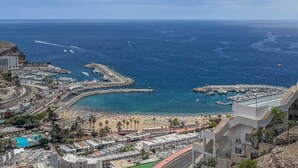Un paisaje urbano costero con un puerto deportivo, playa y edificios residenciales.