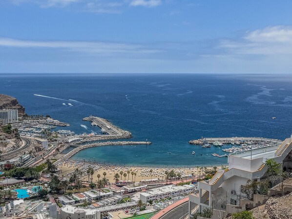 A coastal cityscape with a marina, beach, and residential buildings.