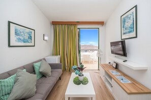 A modern living room with a sofa, a coffee table with a plant, a TV, and a balcony with a view. - Paradise Hill – Terrace & Seaviews (Mogán)