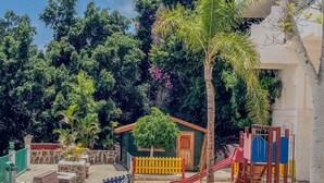 Un parque infantil con tobogán, estructuras para escalar y un edificio pequeño.
