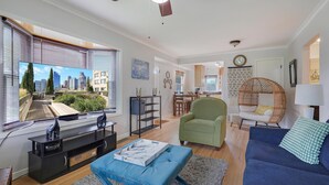 A modern living room with a cityscape view, a ceiling fan, and a dining area in the background. - The Calm & Comfy Nest (Minneapolis)