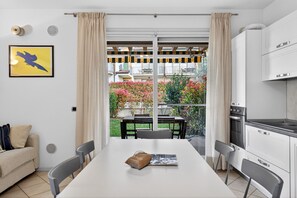 Una cocina moderna con comedor, un sofá y vistas a un balcón con plantas.
