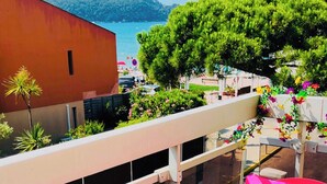 A balcony with a view of the sea, a building with a red facade, and a tree. - Seafront apartment with sea view. Everything within walking distance with parking lot. (Saint-Cyr-sur-Mer)