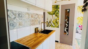 A modern kitchen with a wooden countertop, a black sink, and a decorative backsplash. - Seafront apartment with sea view. Everything within walking distance with parking lot. (Saint-Cyr-sur-Mer)