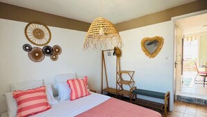 A bedroom with a bed, pillows, a hanging light fixture, wall decorations, and a bench. - Seafront apartment with sea view. Everything within walking distance with parking lot. (Saint-Cyr-sur-Mer)