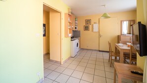 A compact kitchen with a microwave, washing machine, and a dining area with a table and chairs. - Le Cap et la Mer - Vue Mer (Cerbere)