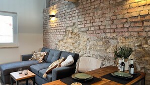 A cozy living area with a brick wall, a grey sofa, a wooden coffee table, and a small side table.