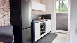 A modern kitchen with a black refrigerator, white cabinets, and a built-in oven.