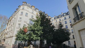 Un edificio de varios pisos con balcones, una entrada con portón y cielo despejado.