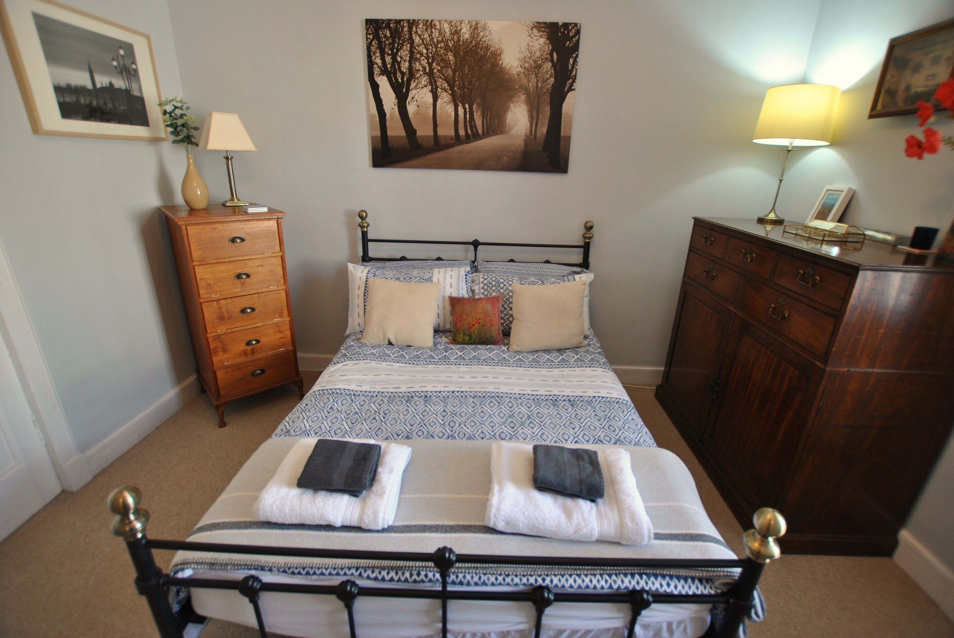Een keurig opgemaakt slaapkamer met een bed, een kaptafel en een ingelijst schilderij aan de muur.