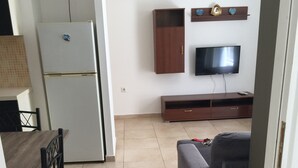 Ein kompakter Wohnbereich mit Küchenzeile, Essbereich, Sofa und flachbildschirm-Fernseher an der Wand.