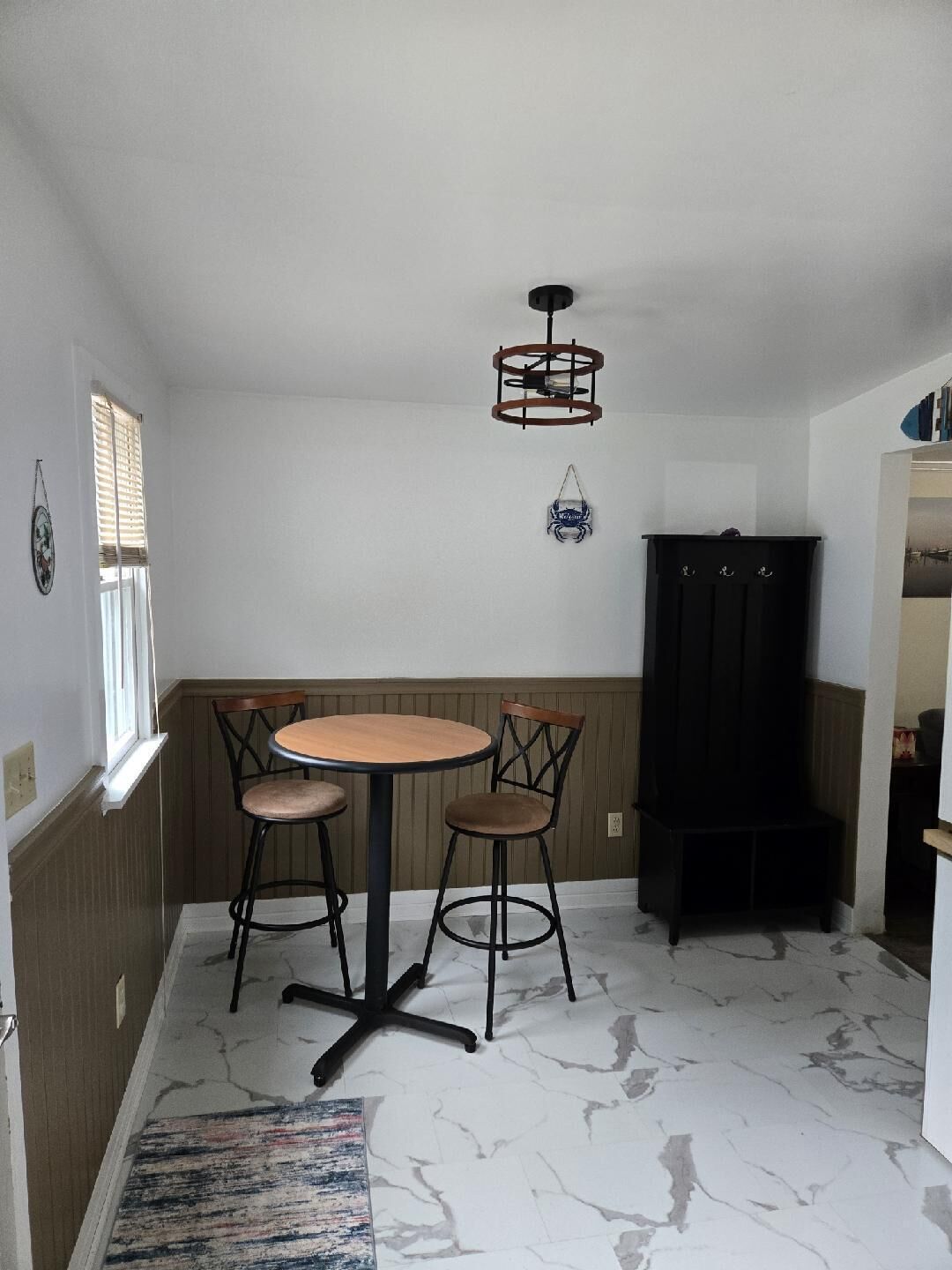A small dining area with a round table and two chairs, a black cabinet, and a ceiling fan.