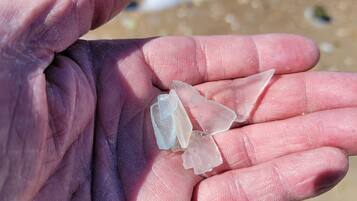 Una mano che tiene cristalli trasparenti su una spiaggia sabbiosa.