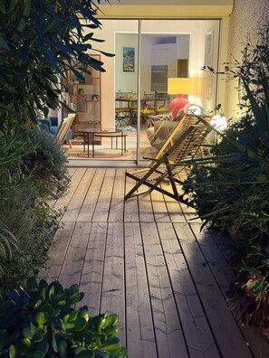 A wooden deck with a lounge chair, surrounded by greenery. - Apartment with small garden and wooden terrace in Cavalaire sur Mer! (Cavalaire-sur-Mer)