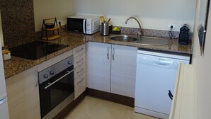 A modern kitchen with granite countertops, stainless steel appliances, and light wood cabinetry.