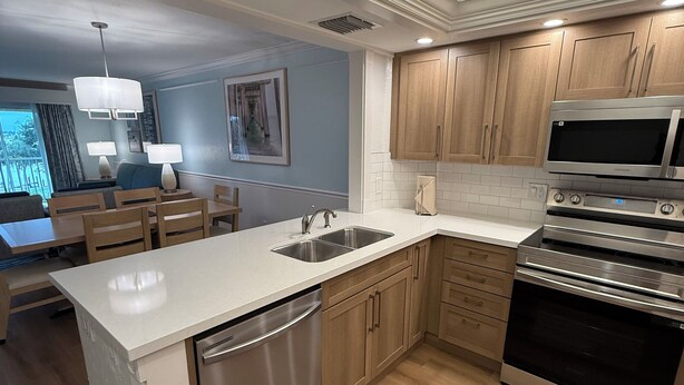 A modern kitchen with wooden cabinets, stainless steel appliances, and a central island with a sink. - Best Resort in Naples, FL,Old Town,Ideal location 2BD/2BA,Property overlooks Bay (Naples)