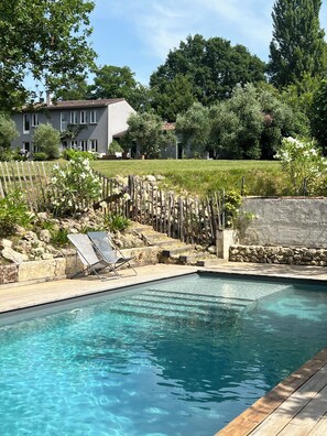 A clear swimming pool with a wooden deck and lounge chairs.