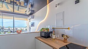 Ett modernt kök med utsikt över staden, en inbyggd mikrovågsugn, ett vinglas och en liten växt på bänkskivan.