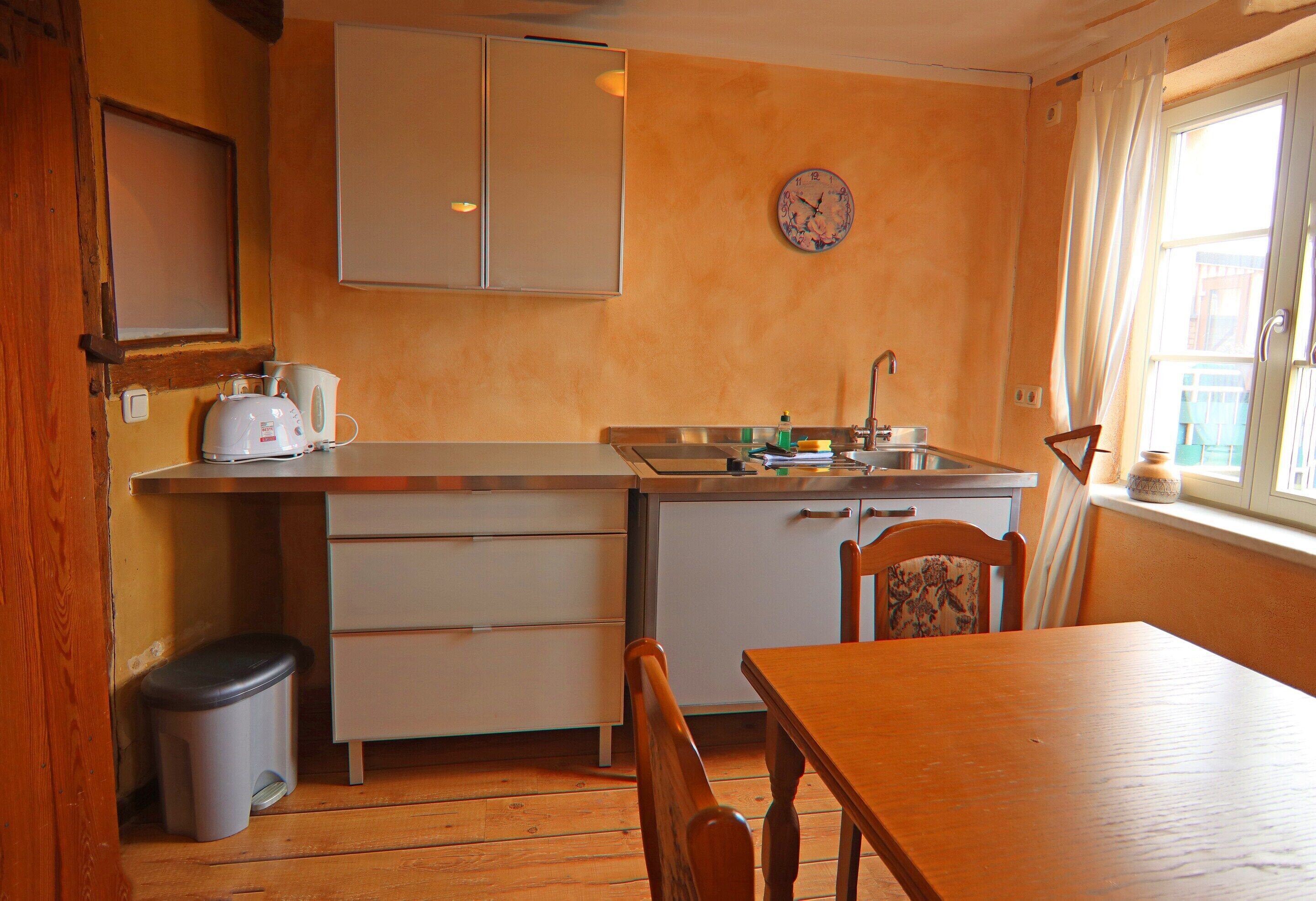 A compact kitchen with a sink, countertop, and wooden dining table.