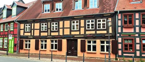 A traditional half-timbered building with a red tiled roof, multiple windows, and a green door.