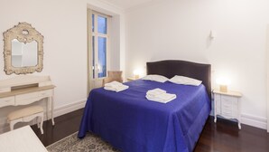 Un dormitorio ordenado con una cama grande, una mesita de noche, un espejo y una ventana.