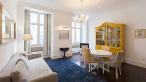 Una sala de estar moderna con un sofá, una mesa de comedor con sillas, una araña y un aparador amarillo.