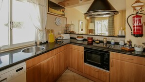 Une cuisine moderne avec des meubles en bois, une cuisinière noire et un évier en acier inoxydable.