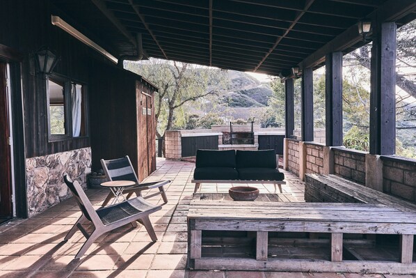 A covered patio with a wooden table, two chairs, and a sofa. - FIVE MINUTES TO CALAMIGOS RANCH AND CEILO FARMS MOUNTAIN AND OCEAN VIEWS (Malibu)