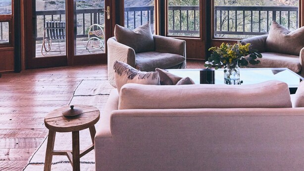 A spacious room with large windows offering a mountain view, a wooden ceiling, and a cozy seating area with a coffee table. - FIVE MINUTES TO CALAMIGOS RANCH AND CEILO FARMS MOUNTAIN AND OCEAN VIEWS (Malibu)