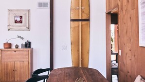 A wooden dining table with chairs, a surfboard, and a decorative bowl. - FIVE MINUTES TO CALAMIGOS RANCH AND CEILO FARMS MOUNTAIN AND OCEAN VIEWS (Malibu)
