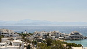 A coastal town with white buildings, a clear view of the sea, and mountains in the distance. - Phaedrus Living: Paros Cycladic Residences 7 (Paros)